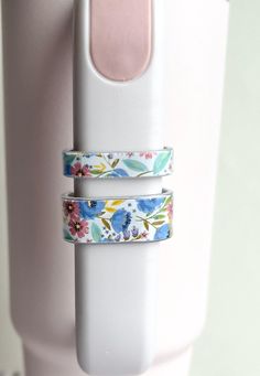 two rings with flowers on them are attached to a white object in front of a pink wall