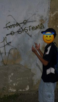 a person with a smiley face painted on the side of a wall and wearing a backpack