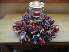 a jar filled with red, white and blue fabric sitting on top of a wooden table