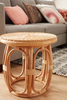 a wicker table sitting on top of a wooden floor next to a gray couch