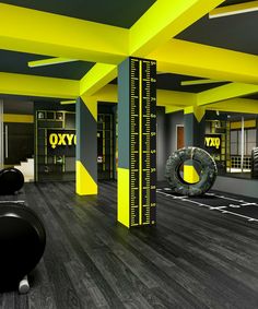 an empty gym with yellow and grey walls, black flooring and exercise equipment in the foreground