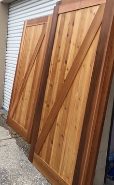 three wooden doors sitting next to each other in front of a garage door with roller shutters