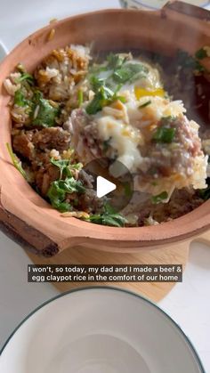 a wooden bowl filled with food on top of a white table next to a plate