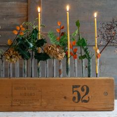 a wooden box with candles and flowers in it