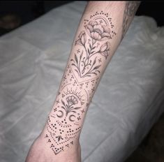 a person's arm with tattoos on it and flowers in the middle of their arm