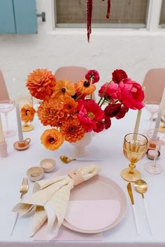 an arrangement of flowers in a white vase on a table with pink and orange napkins