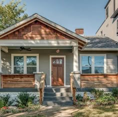 a small gray house with wooden steps leading up to the front door