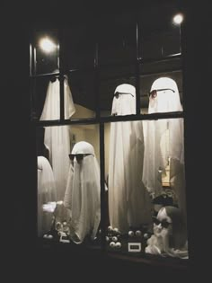 there are many white clothing displayed in the store window with their heads covered by veils