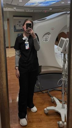 a woman taking a selfie in front of a mirror with a machine behind her