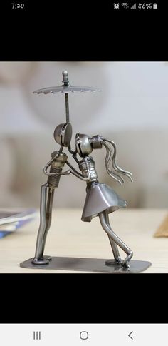 a metal figurine holding an umbrella on top of a table