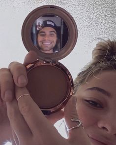 a woman holding up a compact mirror to her face