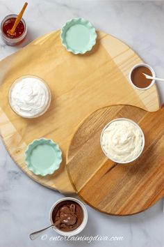 an overhead view of three desserts on a wooden platter with saucers and spoons