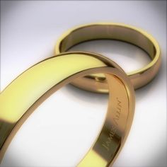 two gold wedding rings sitting next to each other