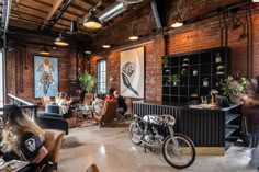 an industrial loft with exposed brick walls and lots of people sitting in chairs, standing around