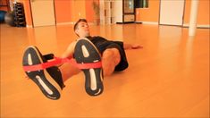 a man laying on the floor with his feet up and holding a red ribbon around his ankles