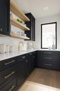 a kitchen with black cabinets and white counter tops, gold pulls on the handles is shown