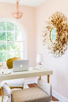 a laptop computer sitting on top of a desk in front of a round mirror and window