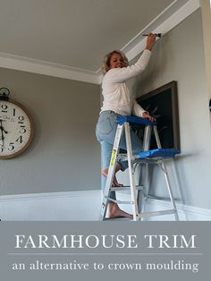 a woman standing on a ladder painting the ceiling in her house with text overlay that reads, farmhouse trim an alternative to crown molding