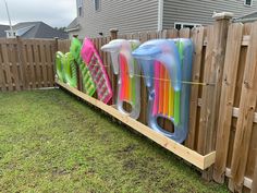 a row of plastic toys sitting on top of a wooden fence