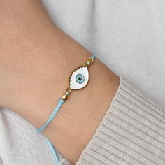 a woman wearing a bracelet with an evil eye on it's side and a blue cord around her arm