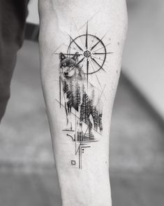 a man's leg with a wolf and compass tattoo on it