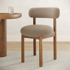 a wooden chair sitting next to a table on top of a carpeted floor in front of a white wall