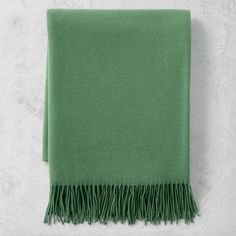 a green blanket with fringes on it