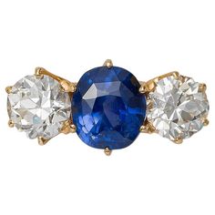 three stone ring with blue and white stones on the front, set in yellow gold