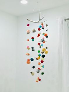 a white room with a deer antler hanging from the ceiling and colorful pom - poms on the wall