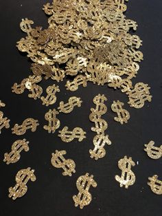 gold sequinized dollar signs are scattered on a black surface