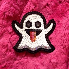 a patch with a ghost on it sitting on top of a pink fur covered surface