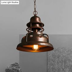 a light that is hanging from the ceiling in a room with gray walls and rocks