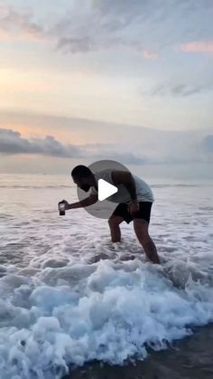 a man is standing in the ocean with his surfboard