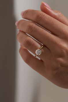 a woman's hand wearing a gold ring with a diamond on the middle finger