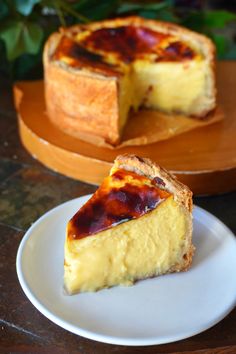 a piece of cheesecake on a plate next to a wooden platter with a slice missing