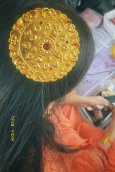 the back of a woman's head with a gold brooch on top of it