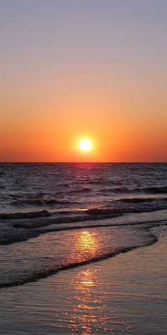 the sun is setting over the water at the beach