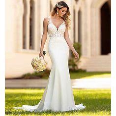 a woman in a white wedding dress is walking through the grass with her bouquet on her hand