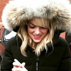 a woman wearing a fur hat looking at her cell phone