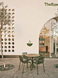 an outdoor table and chairs in front of a white wall with the bow logo on it