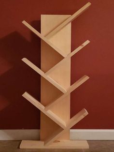 a wooden book shelf sitting on top of a hard wood floor next to a red wall