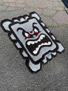 a black and white sticker with red eyes on the ground next to a skateboard