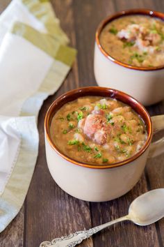 two bowls of creamy white bean and ham hock soup with spoons on the side