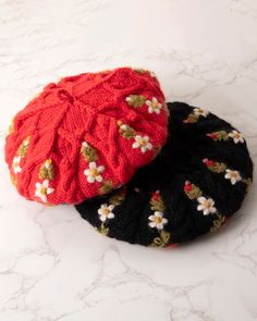 two knitted hats sitting on top of a white countertop next to each other