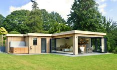 a small wooden building sitting in the middle of a lush green field next to trees