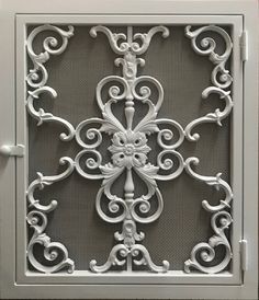 an intricately designed metal grille on the side of a building, with white paint