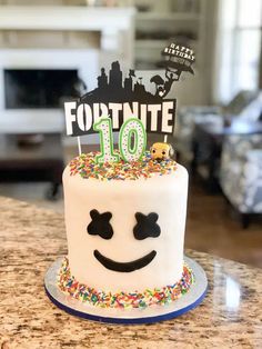 a white cake with sprinkles and a happy face on top that says fortnite 10