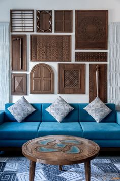 a blue couch sitting in front of a wall covered with wooden plaques and other decorative items