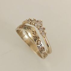 two gold wedding rings with flowers and leaves on each band, set against a white background