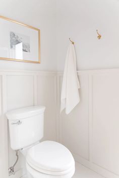 a white toilet sitting in a bathroom next to a towel